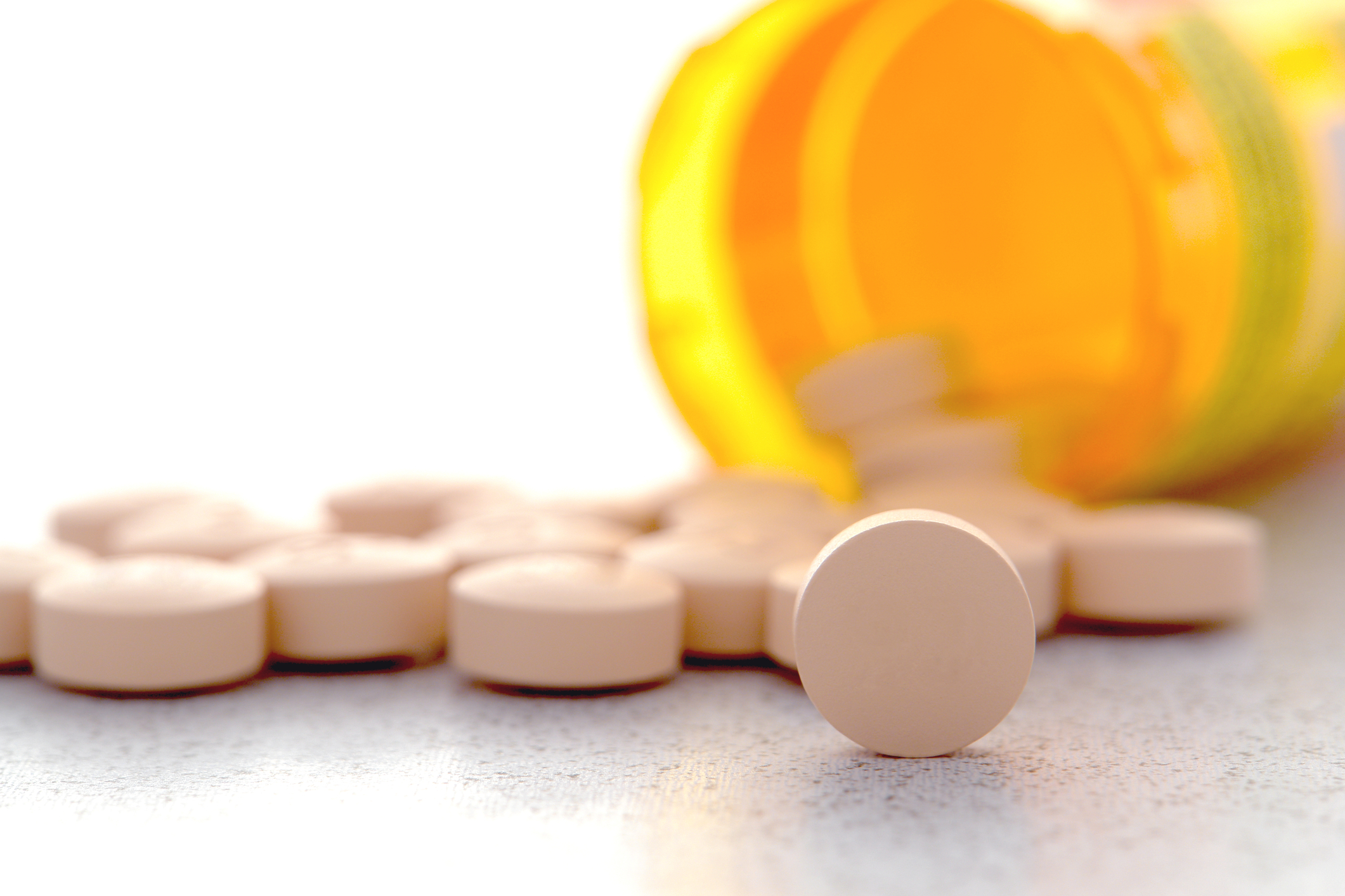 En medicinburk som välts så att tabletterna ramlat ut på bordet.